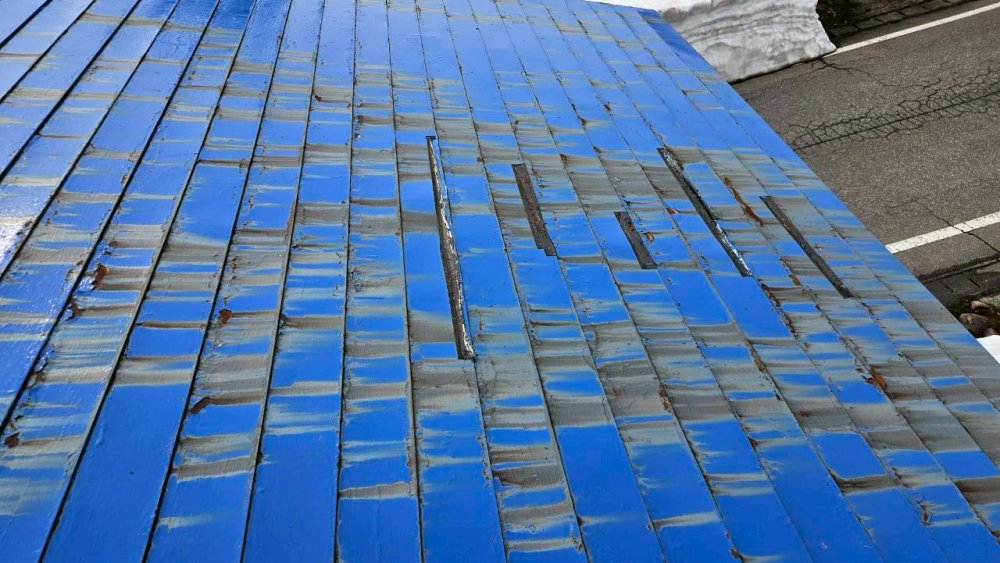 施工前の屋根。青い塗装が色褪せ、板金の継ぎ目に破損が見られる状態